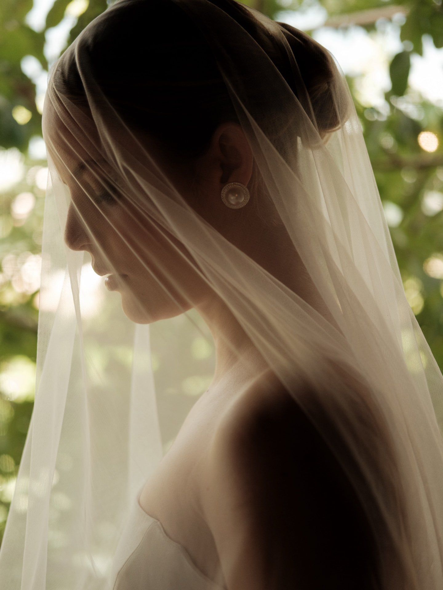 Noiva de perfil sob o véu na luz do jardim